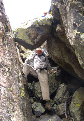 Gerry descending under the chockstone that is near the top of the upper gully on the south face of the South Peak